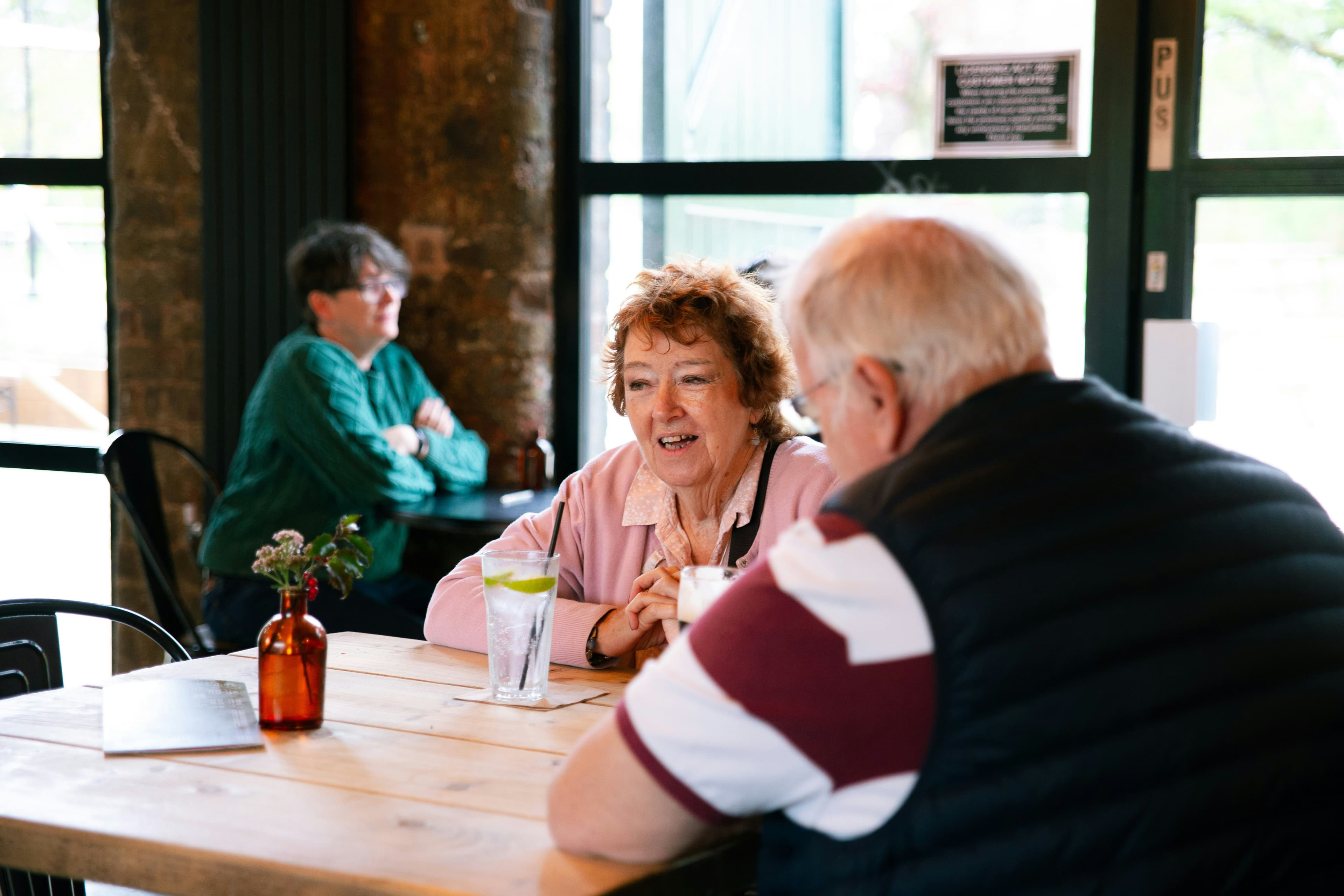 Two older adults talking over drinks across a cafe table